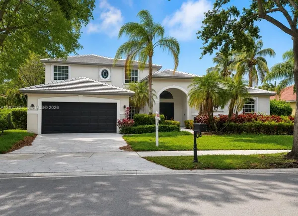 a front view of a house with a garden and palm trees
