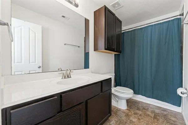 a bathroom with a sink a toilet a mirror and shower curtain