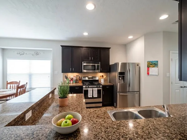 a kitchen with stainless steel appliances granite countertop a sink a stove and a refrigerator