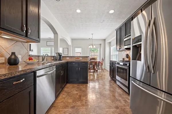 a kitchen with stainless steel appliances granite countertop a refrigerator a sink a stove and island