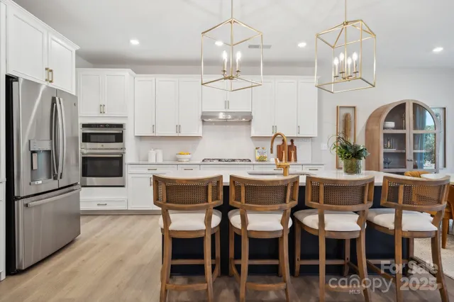 a dining area with stainless steel appliances kitchen island granite countertop a table chairs and a refrigerator