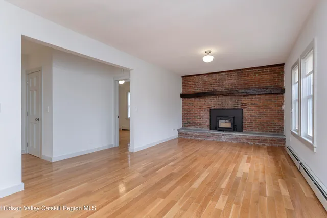 a view of empty room with wooden floor and fireplace