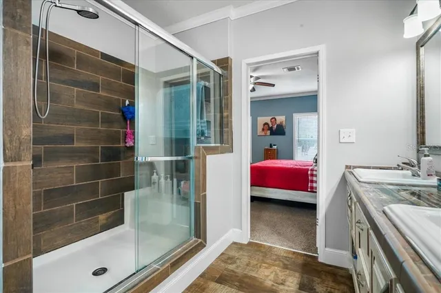 a en suite bathroom with a granite countertop sink a mirror and shower