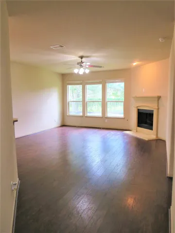 a view of empty room with wooden floor and fan