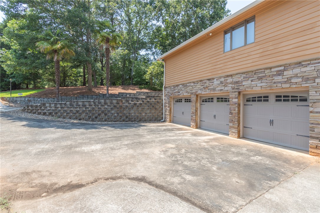 202 Plantation Point Anderson, SC 29625 - Photo 5 of 48 A spacious driveway leads to a three-car garage with attractive stone and siding details.