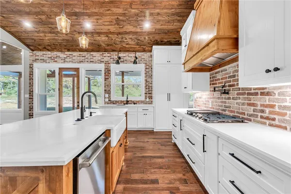 a large kitchen with stainless steel appliances granite countertop a lot of counter space and a wooden floors