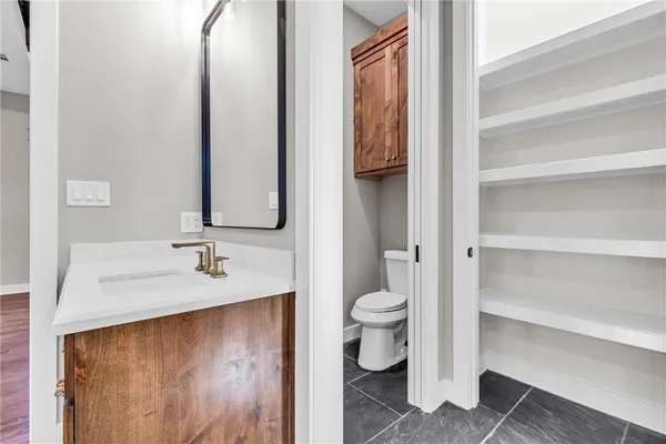 a bathroom with a granite countertop sink toilet and mirror