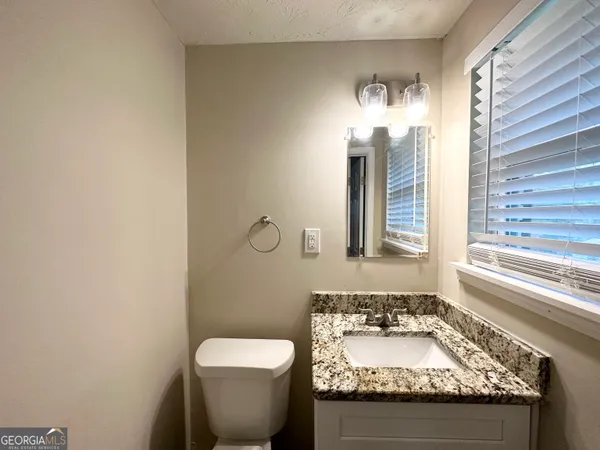 a bathroom with a granite countertop sink and a toilet