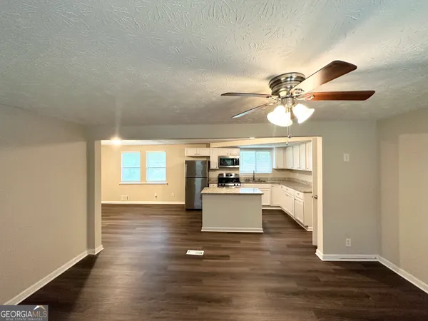 a living room with couches and kitchen view with wooden floor