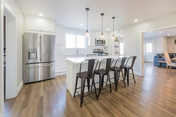 a kitchen with stainless steel appliances a dining table chairs stove refrigerator and wooden floor