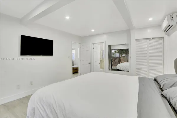 a bedroom with a bed a flat screen tv and a white bed