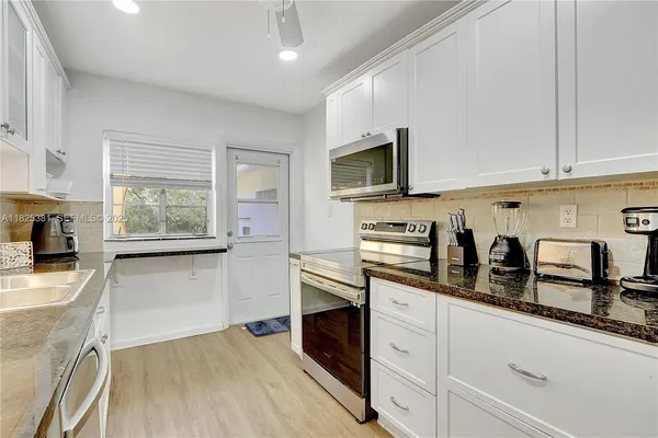 a kitchen with stainless steel appliances white cabinets a sink and a wooden floor
