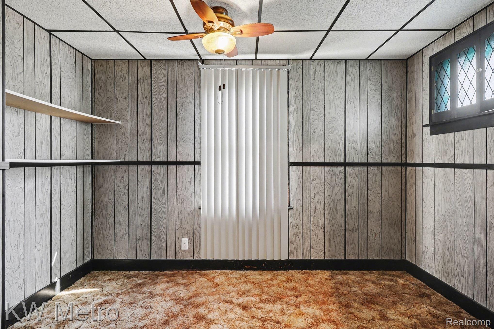 85 Walnut Street River Rouge, MI 48218 - Photo 16 of 20 Empty room with ceiling fan, a drop ceiling, wood walls, and carpet