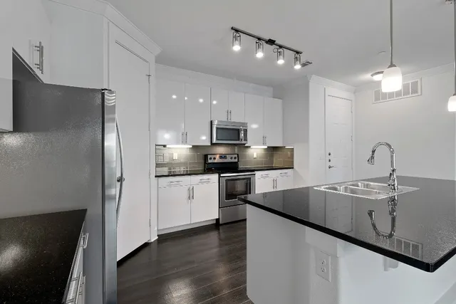 a kitchen with stainless steel appliances granite countertop a sink a stove a refrigerator and island with wooden floor