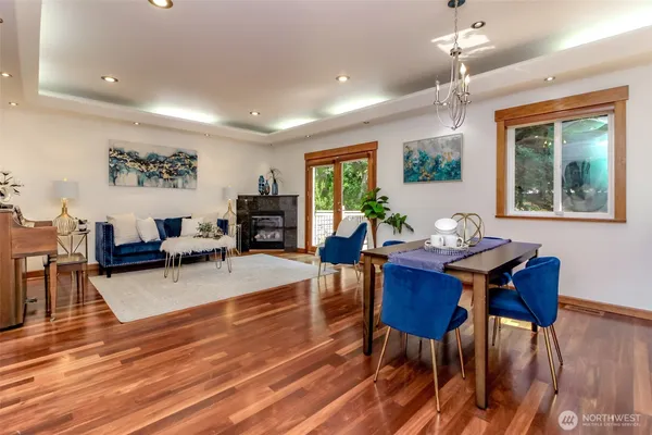 a living room with furniture dining table a large window and wooden floor
