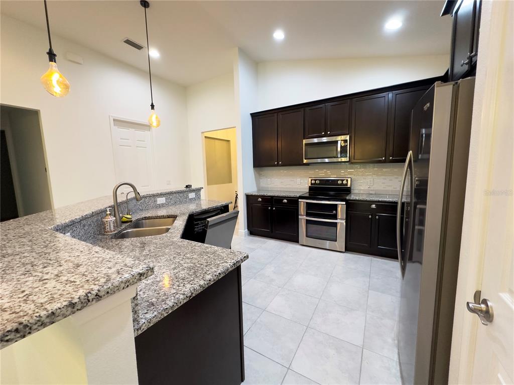 3775 Manorwood Loop Parrish, FL 34219 - Photo 11 of 30 a kitchen with stainless steel appliances granite countertop a sink and a stove