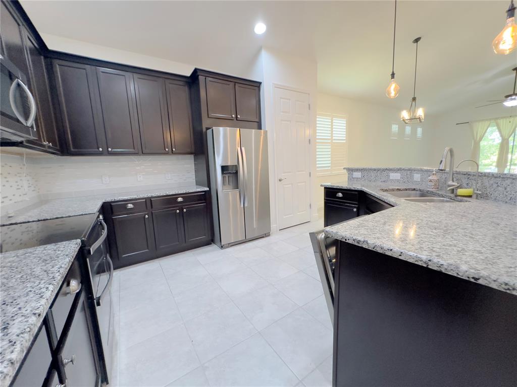 3775 Manorwood Loop Parrish, FL 34219 - Photo 10 of 30 a kitchen with stainless steel appliances granite countertop a sink a stove and a refrigerator