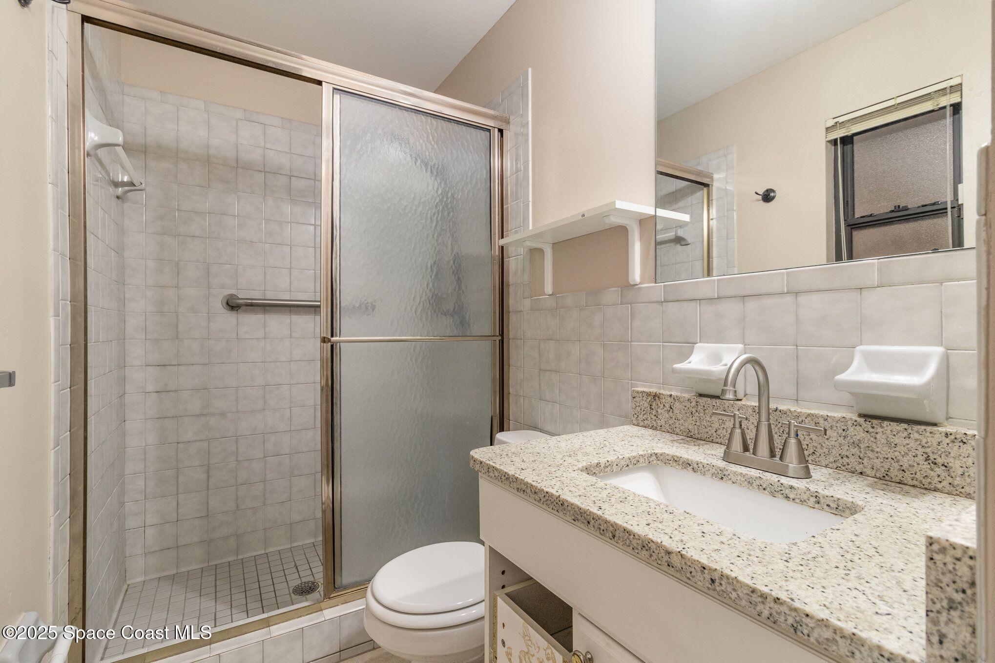 2863 Corbusier Drive Melbourne, FL 32935 - Photo 11 of 20 a bathroom with a granite countertop sink toilet and shower