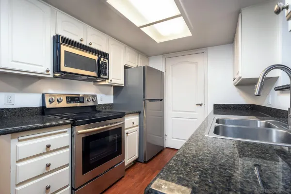 a bathroom with a granite countertop bathtub shower sink vanity and toilet