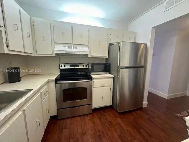 a kitchen with cabinets stainless steel appliances and wooden floor