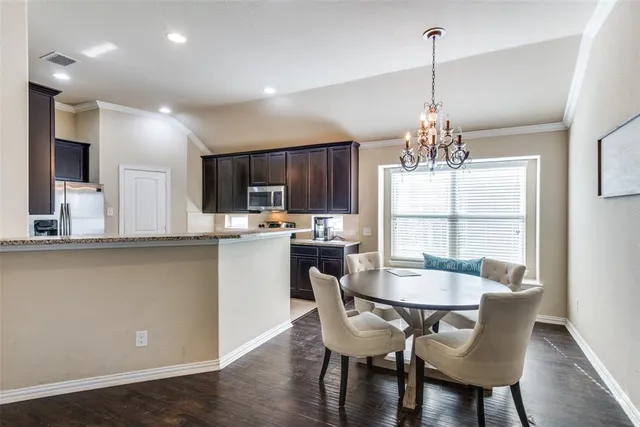 a dining room with stainless steel appliances kitchen island granite countertop a dining table chairs and a chandelier