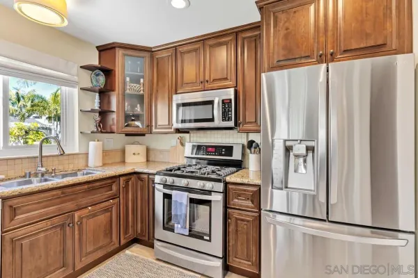 a kitchen with stainless steel appliances granite countertop a sink a stove and a counter space