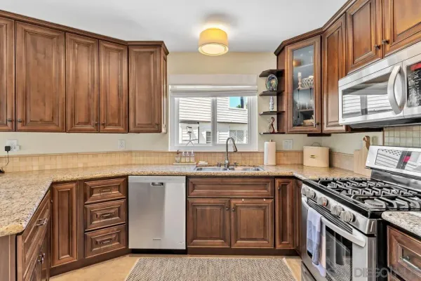 a kitchen with granite countertop a sink dishwasher stove and cabinets
