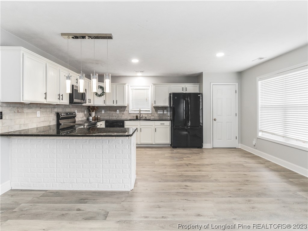 1964 Yellowbrick Road Fayetteville, NC 28314 - Photo 12 of 37 a large kitchen with stainless steel appliances granite countertop a stove a refrigerator a sink a refrigerator and white cabinets with wooden floor