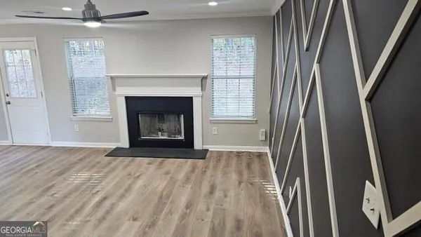 an empty room with wooden floor fireplace and windows