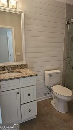 a bathroom with a granite countertop toilet and sink