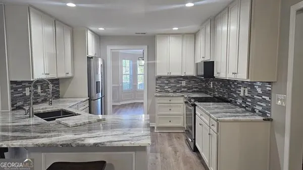 a kitchen with stainless steel appliances granite countertop a stove a sink and a refrigerator