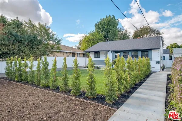 a front view of a house with a yard and potted plants