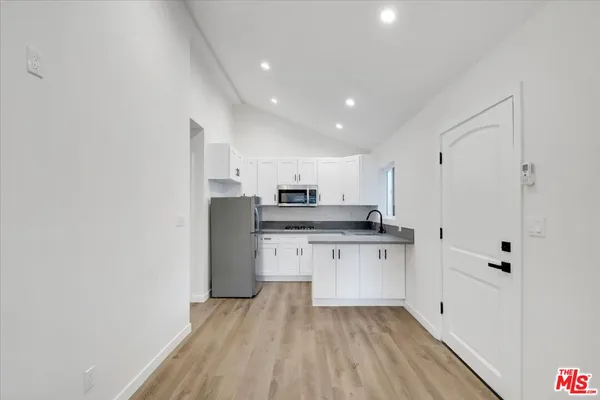 a kitchen with stainless steel appliances a refrigerator sink and white cabinets