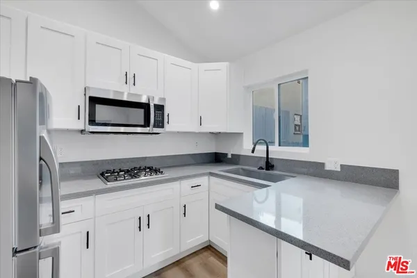a kitchen with granite countertop a sink stove top oven and cabinets
