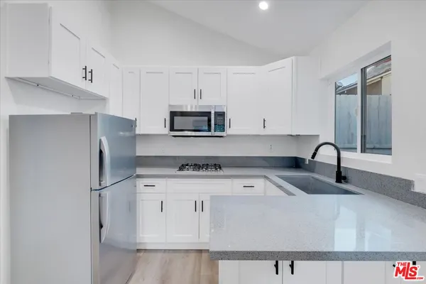 a kitchen with stainless steel appliances granite countertop a refrigerator sink and white cabinets