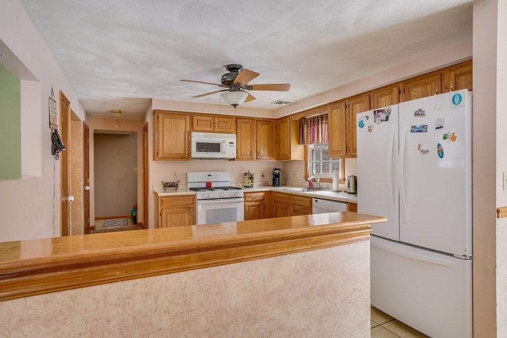 1109 Whipple Road Tewksbury, MA 01876 - Photo 18 of 25 a kitchen with stainless steel appliances granite countertop a refrigerator a stove and a sink with wooden floor