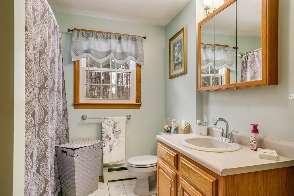 1109 Whipple Road Tewksbury, MA 01876 - Photo 5 of 25 a bathroom with a sink a mirror a toilet and a window