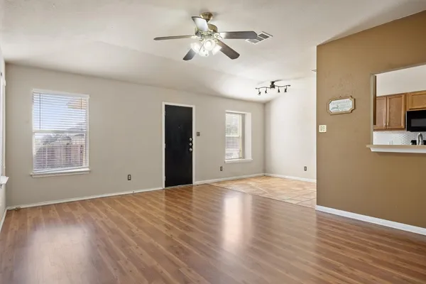 a view of an empty room with a window and wooden floor
