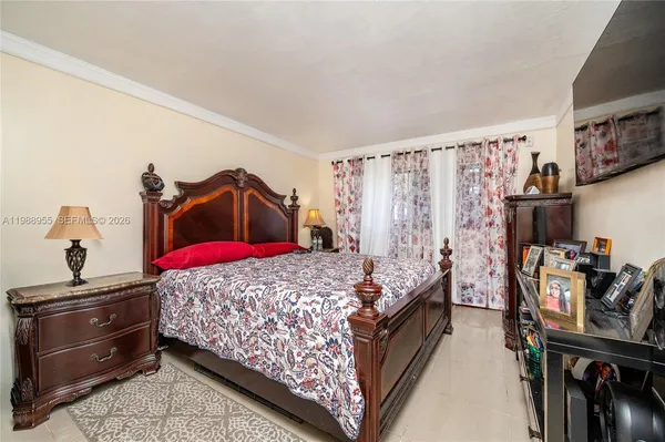 a bedroom with a bed and a flat tv screen on the dresser
