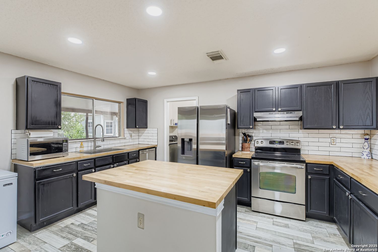 8614 Cross Spring San Antonio, TX 78251 - Photo 8 of 24 a kitchen with stainless steel appliances kitchen island granite countertop a stove sink and refrigerator