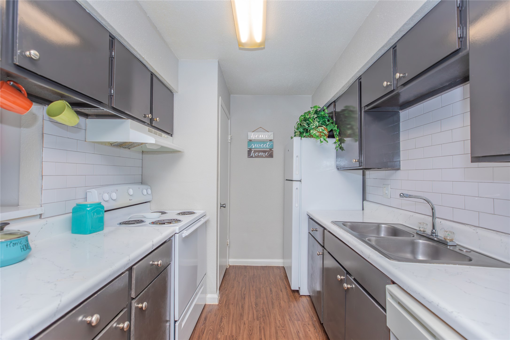 a kitchen with a sink a counter space cabinets and wooden floor