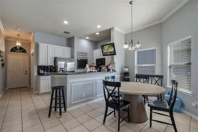 a kitchen with stainless steel appliances kitchen island granite countertop a dining table chairs and a refrigerator