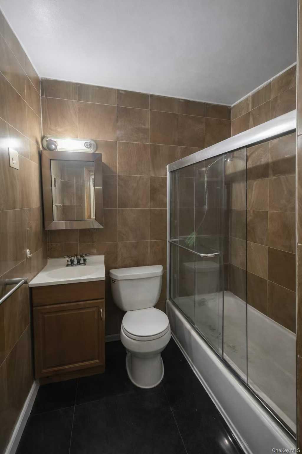 37-33 107th Street, Unit 4A Queens, NY 11368 - Photo 6 of 7 a bathroom with a sink and mirror with toilet