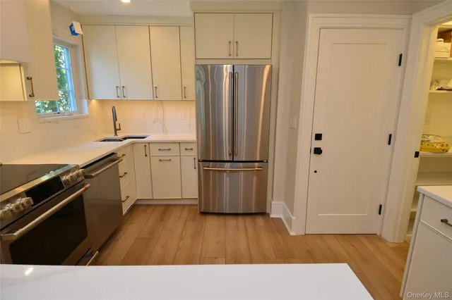 a kitchen with stainless steel appliances a refrigerator and wooden floor