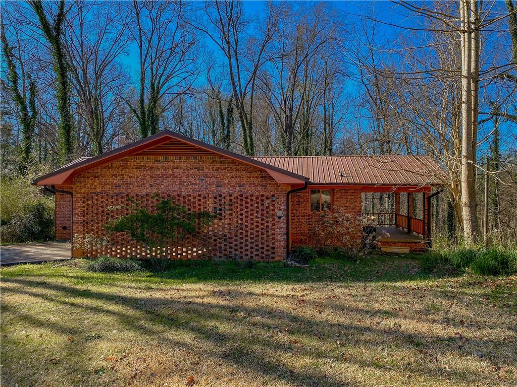707 Campbell Town Road Walhalla, SC 29691 - Photo 2 of 19 Brick exterior home with an inviting covered porch, nestled amongst mature trees, offering a private, tranquil setting.