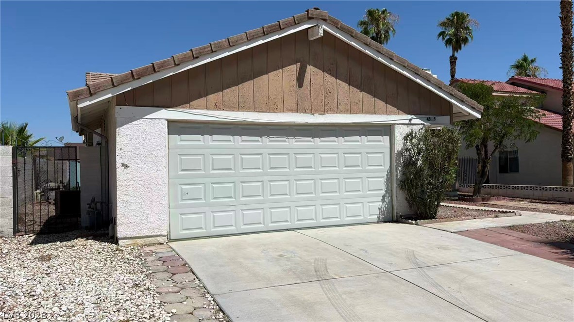 4325 Newcastle Road Las Vegas, NV 89103 - Photo 2 of 18 A classic garage entry with a concrete driveway and an inviting side gate, perfect for convenient access.