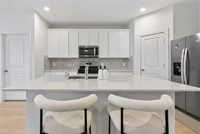 a kitchen with stainless steel appliances a table chairs refrigerator and microwave