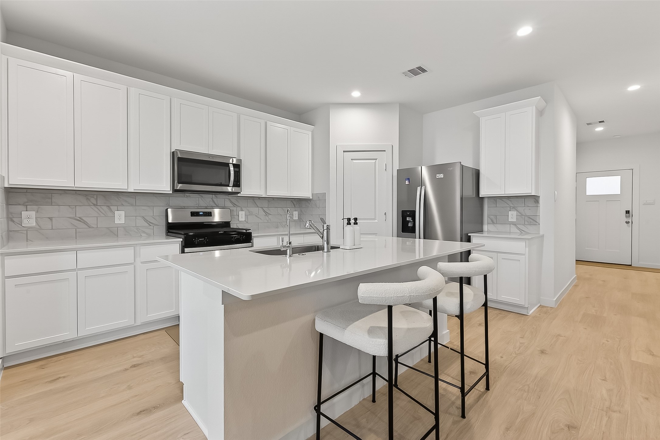 3903 Dodington Ash Drive Fulshear, TX 77441 - Photo 13 of 46 a kitchen with a refrigerator a stove a sink and white cabinets with wooden floor
