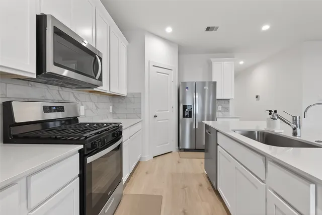 a kitchen with stainless steel appliances granite countertop a sink a stove a refrigerator and a microwave