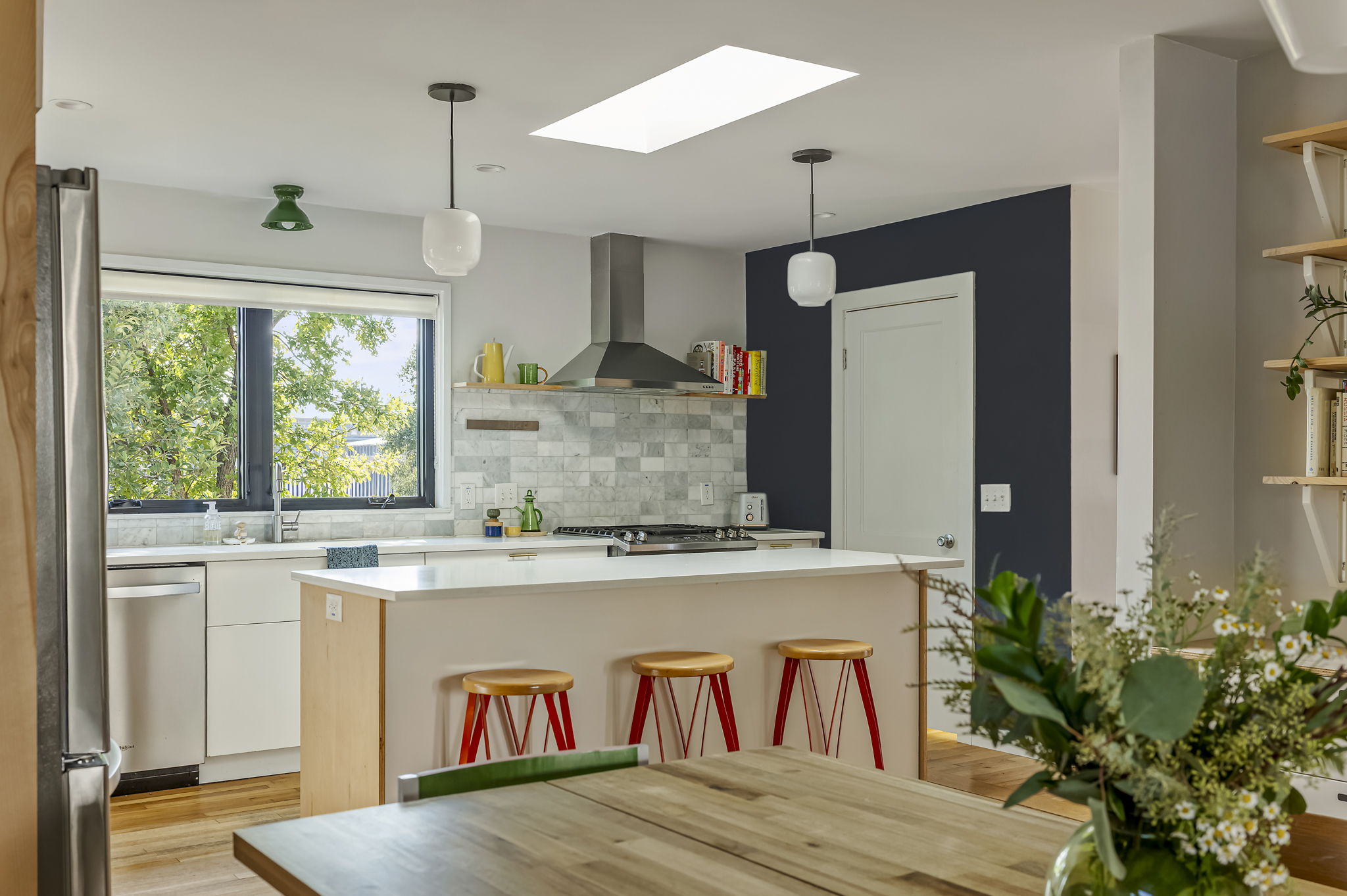 618 Denson Drive Austin, TX 78752 - Photo 9 of 35 a kitchen with kitchen island a stove a refrigerator and a dining table with wooden floor